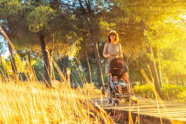 A young woman walking with her son along the wooden walkway in the Doñana natural park at sunset